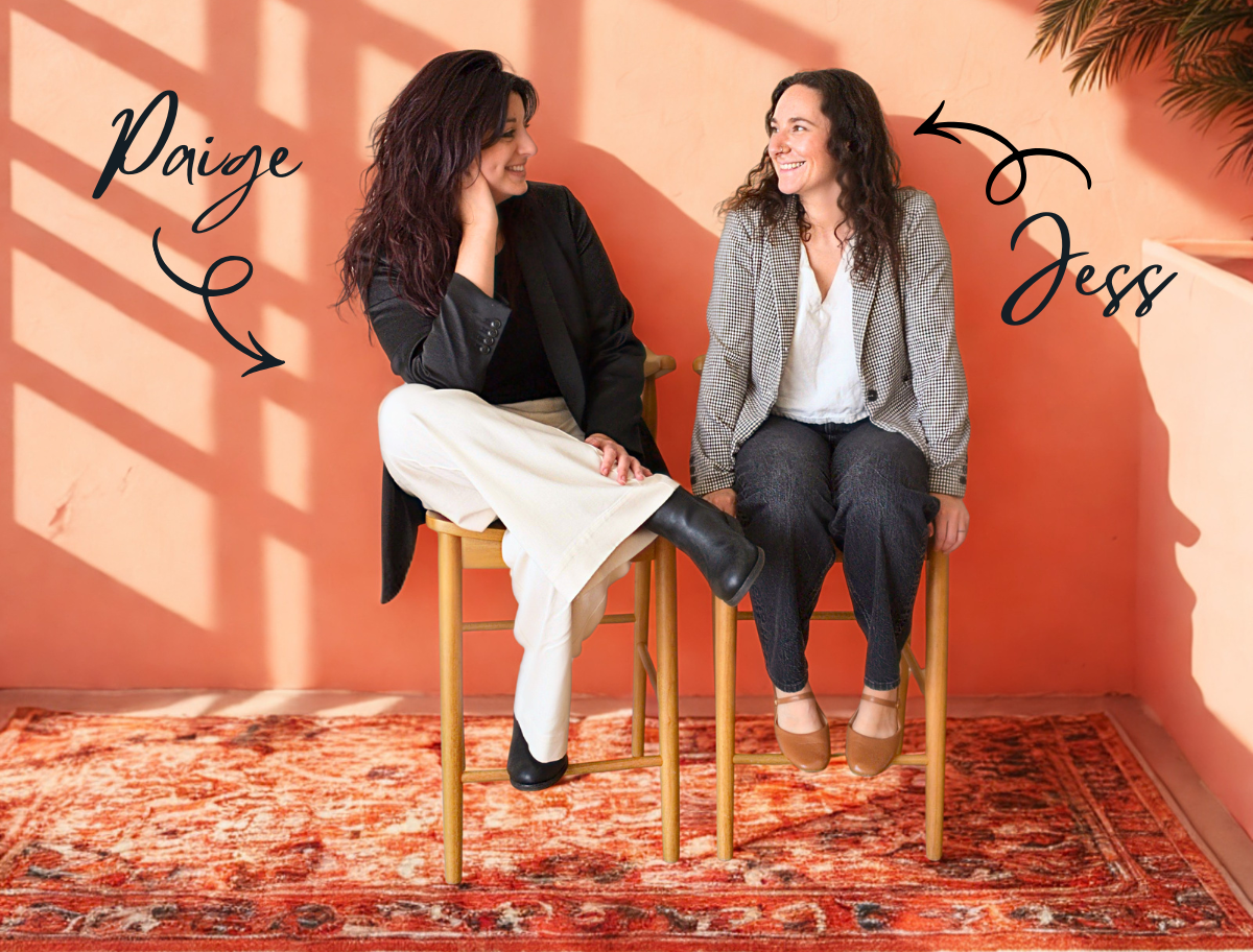 The Toast Society founders sitting on stools against a warm coral wall